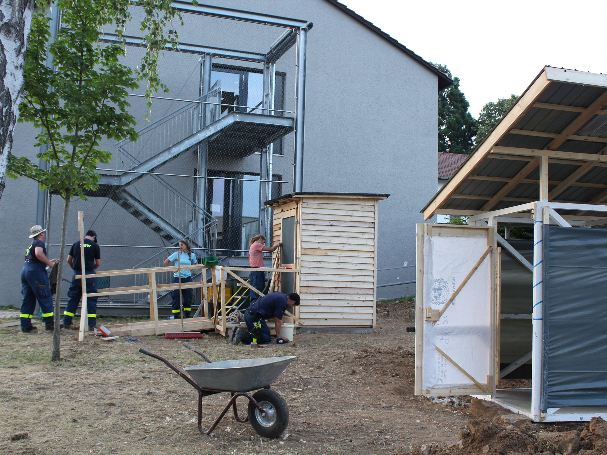 Teilnehmer*innen des Simulationstraining des Technischen Hilfswerks bauen eine Rampe, um Rollstuhlfahrer*innen den Zugang zur Latrine zu ermöglichen.