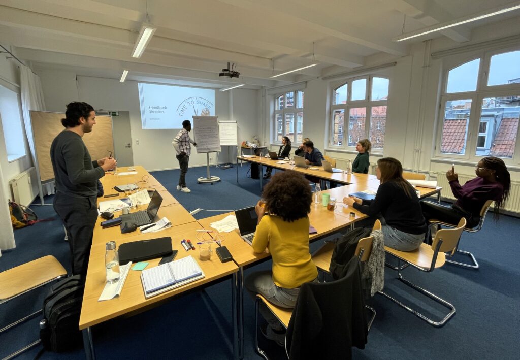 Training participants sitting in U-form and listening while one participant is presenting in front of the room.