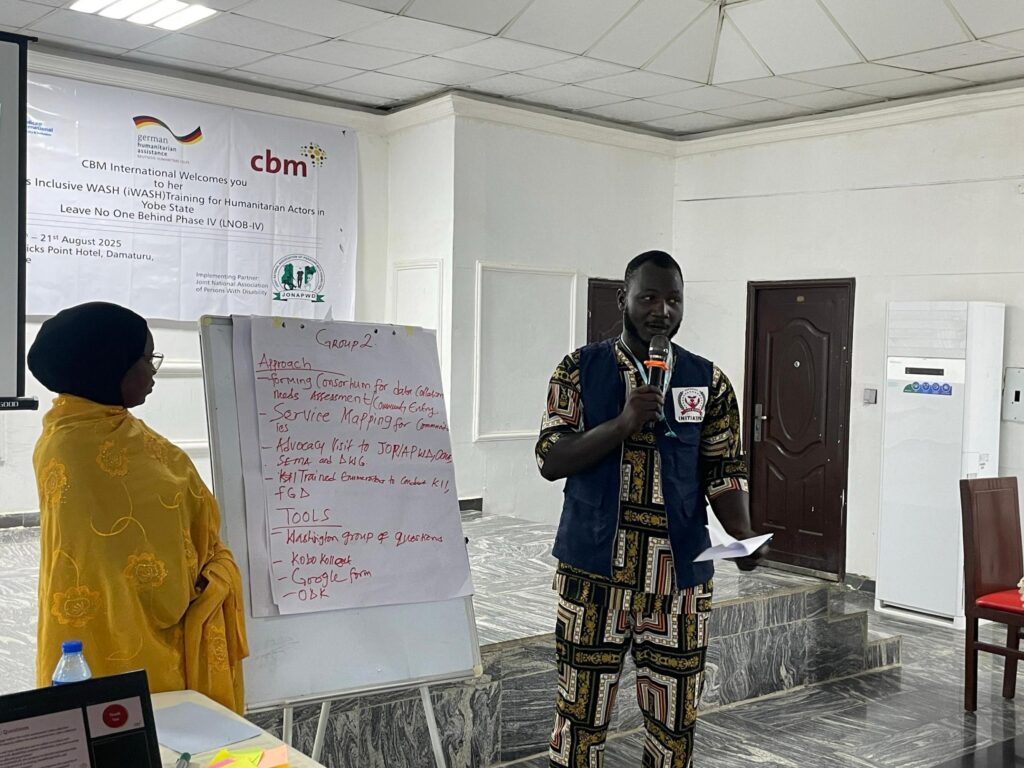 Two participants are actively engaged in an Inclusive WASH training session in Damaturu, Yobe State, presenting the findings of their group work to the audience. © CBM