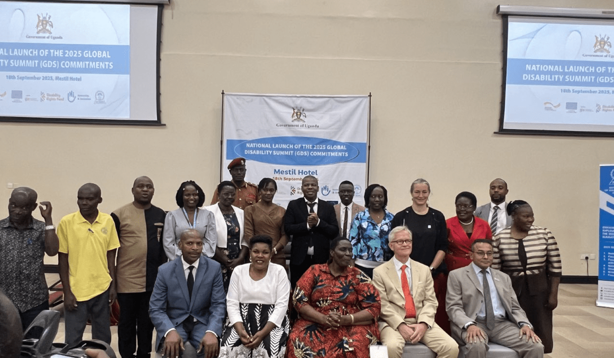 Group photo of event participants standing and seated in front of banners for the National Launch of the 2025 Global Disability Summit Commitments in Uganda.