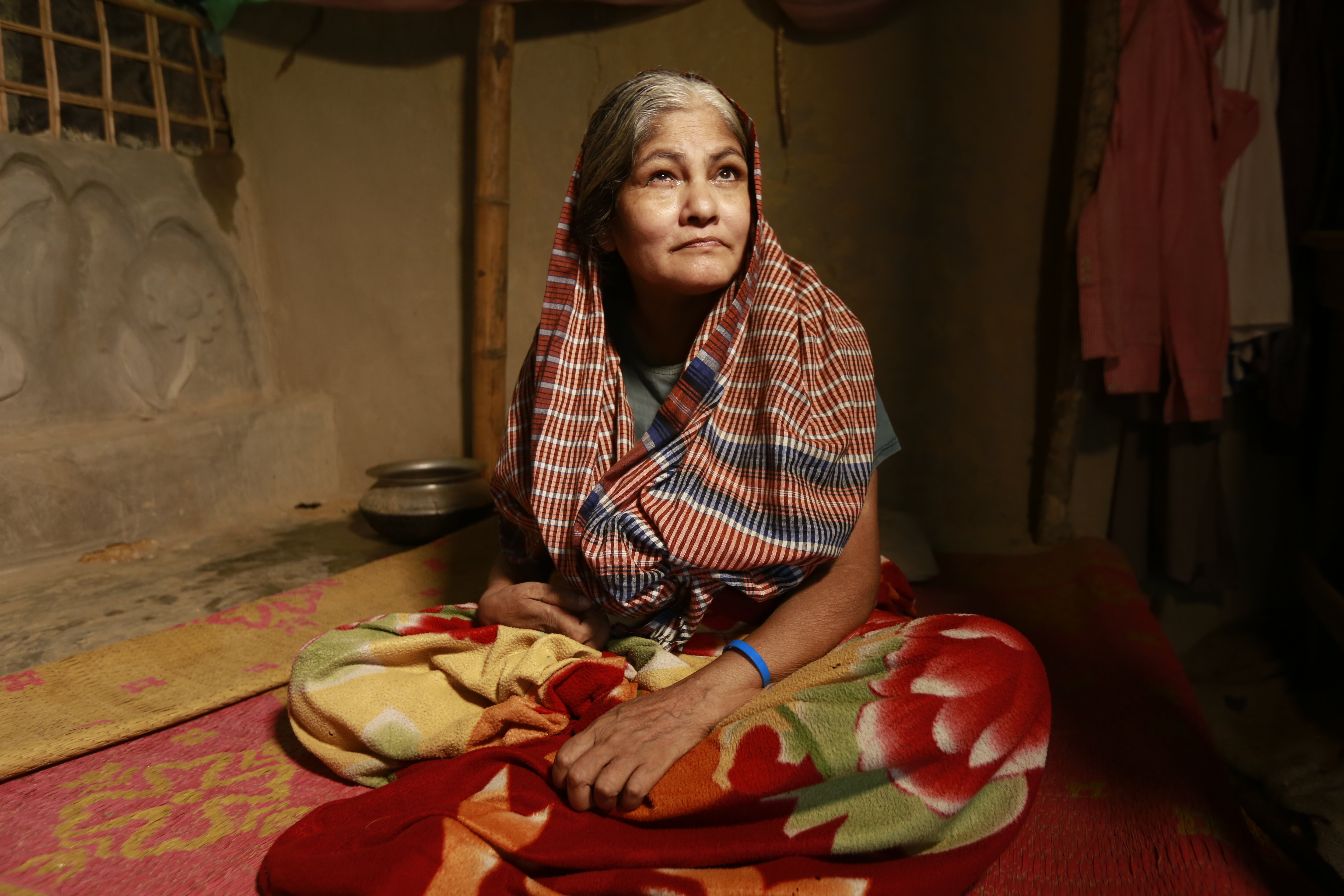 Dieses Foto zeigt eine ältere Frau mit physischer Beeinträchtigung sitzend in einem Haus.