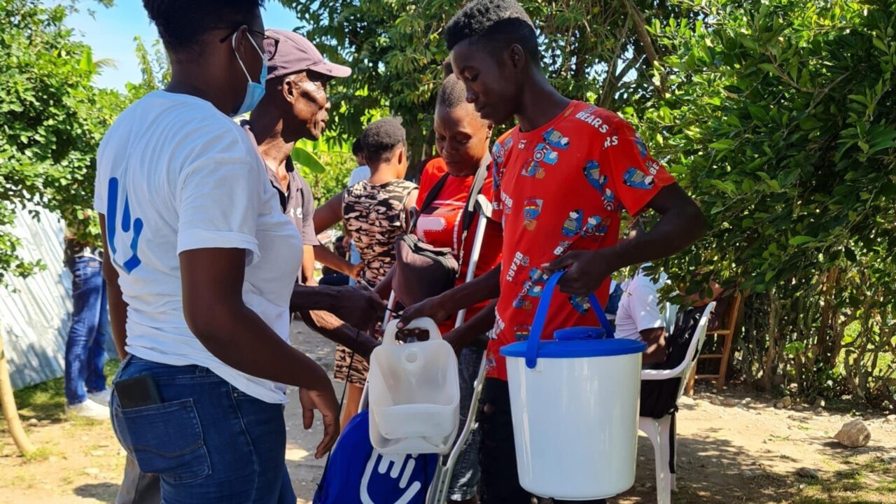 Woman distributing hygiene kits to persons.