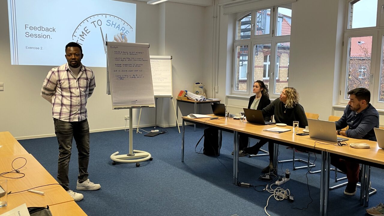A training participant is standing in front of the group and presenting the discussion outcomes.