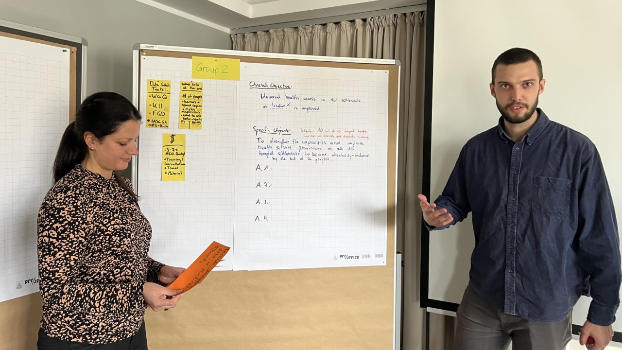 Two training participants presenting the findings of the group work in front of the flipchart.